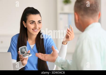 Ärztin zeigt Hörgerät in der Klinik Stockfoto
