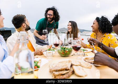 Gruppe junger multirassischer Freunde, die im Sommer auf der Terrasse zu Abend essen Stockfoto