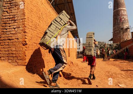 Arbeiter transportieren schwere Steine in einem Ofen in Nepal. Stockfoto