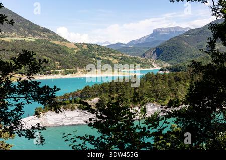 Ein malerischer Blick auf einen pulsierenden türkisfarbenen See, umgeben von üppigem Grün und majestätischen Bergen. Stockfoto
