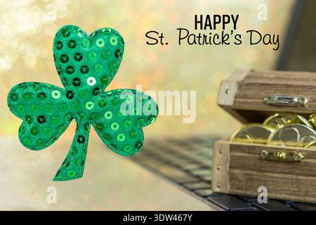 Happy St. Patrick's Day, schwimmendes Shamrock und Gold auf Laptop Stockfoto