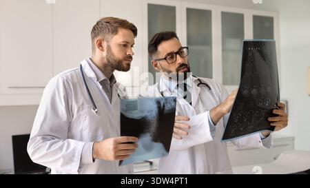 Zwei junge Ärztinnen und Chirurgen vergleichen Patientenröntgen diskutieren Diagnose Stockfoto