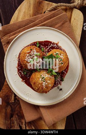 Knusprige Arancini-Vorspeise mit Parmesan und Mikrogrün, Teller, Tomatensauce, hausgemacht, keine Leute Stockfoto