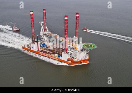 Esbjerg, Dänemark - 15. Februar 2026: Luftaufnahme eines großen, orangen und weißen Offshore-Installationsschiffs, das durch das dunkle Wasser schneidet, dessen rotes und weißes Wasser Stockfoto