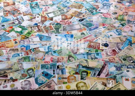 Viele Banknoten unterschiedlicher Währung. Eine große Menge von zufälligen Geldrechnungen aus der Nähe. Währungsumtausch-Konzept Stockfoto