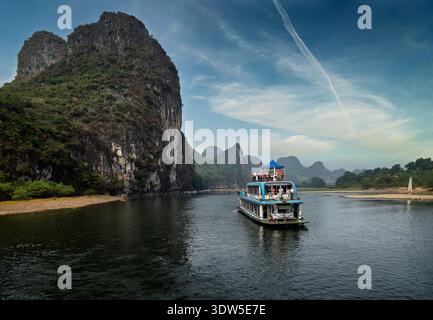 Kreuzfahrtschiffe auf dem Li-Fluss bei Sonnenuntergang mit Karstbergen in Guangxi, China Stockfoto