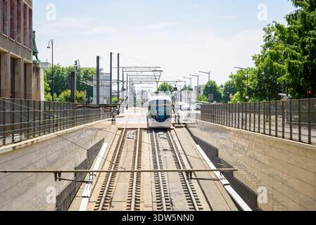 Moderne Straßenbahn auf der Zufahrt, die an einem sonnigen Sommertag zu einer Brücke im Stadtzentrum führt Stockfoto