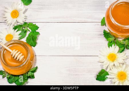 Frischer Honig in einem Glas auf hölzernem Hintergrund mit Gänseblümchen, Banner, Werbung Stockfoto