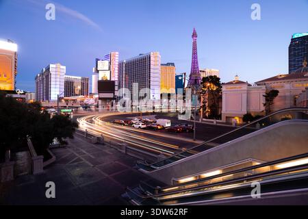 Der Blick auf die leuchtenden Lichtstreifen vorbeifahrender Autos beleuchtet die belebten Straßen unter den hoch aufragenden Gebäuden, wobei der Eiffelturm hoch steht. Stockfoto