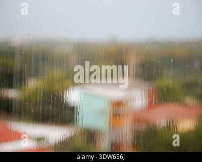 Ein verschwommener Blick auf eine Stadt mit viel Regen. Der Regen lässt die Fenster der Gebäude verschwimmen und der Blick auf die Stadt ist verzerrt Stockfoto