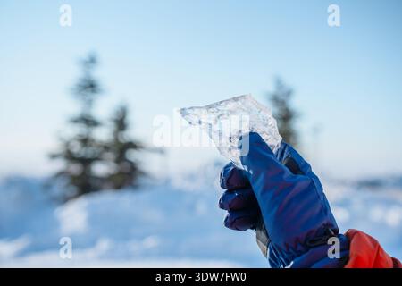 Ein Mann hält im Winter draußen ein Stück Eis Stockfoto