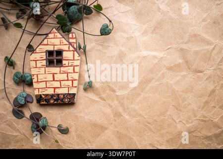 Hölzerne Hausform auf zerknittertem Kraftpapierhintergrund. Immobilien, Hauskonzept, Öko-Stil und Kopierraum. Stockfoto