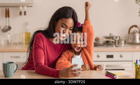 Lächelnde Mutter und Tochter teilen sich einen freudigen Moment, während sie ein Selfie drinnen machen Stockfoto
