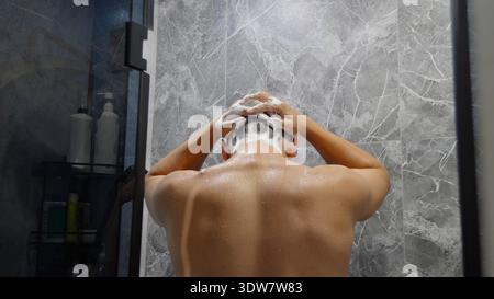 Rückansicht eines Mannes, der seine Haare in der Dusche wäscht Stockfoto