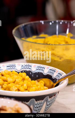 Schüssel mit süßem Mais mit Hummus im Hintergrund auf Küchentisch Stockfoto