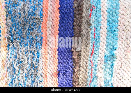Traditioneller rustikaler Teppich mit einem gestreiften Muster. Hintergrund eines mehrfarbigen Teppichs. Traditioneller, rustikaler, sehr langer Teppich. Stockfoto