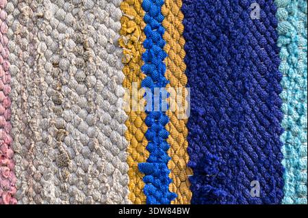 Traditioneller rustikaler Teppich mit einem gestreiften Muster. Hintergrund eines mehrfarbigen Teppichs. Traditioneller, rustikaler, sehr langer Teppich. Stockfoto
