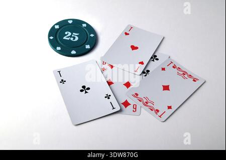 Aces spielen Karten mit einem 25 usd Casino Chip auf weißem Hintergrund. Stockfoto