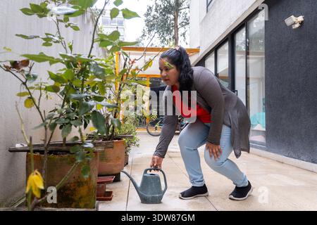 Frau pflegt Pflanzen auf einer Terrasse im Freien und beschäftigt sich als Hobby mit Gartenarbeit Stockfoto