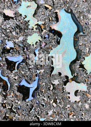Farbenfroher Ölputz auf nassem Asphalt sorgt für Regenbogenreflexe und schillernde Muster in Pfützen nach Regen. Stockfoto