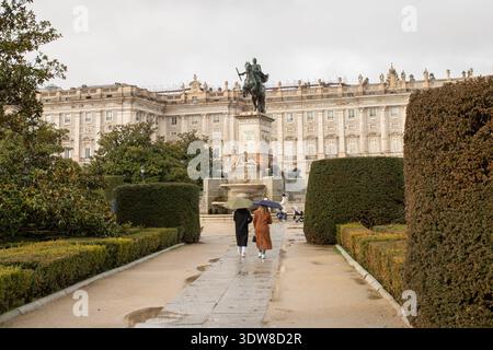 Ein Paar, das an einem regnerischen Tag in den Sabatini-Gärten mit dem Königspalast im Hintergrund spaziert, Madrid, Spanien. Stockfoto