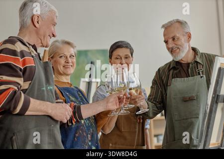 Gruppe von älteren kaukasischen Künstlern feiert Erfolge während des Kunstkurses Stockfoto