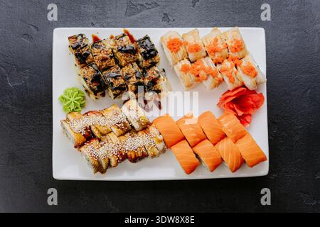 Verschiedene Sushi-Brötchen mit Lachsaal und Tobiko, serviert auf weißem Teller mit Blick von oben Stockfoto