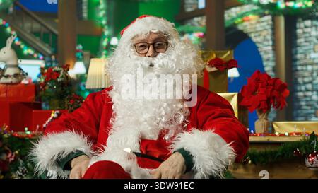 POV von Santa Claus, der Online-Videoaufnahmen mit Kindern macht, die dieses Jahr nett waren. Ältere Person mit falschem Bart, die Internet-Videokonferenzen macht, sich darauf vorbereitet, Kinder zu besuchen, Kamera A Stockfoto
