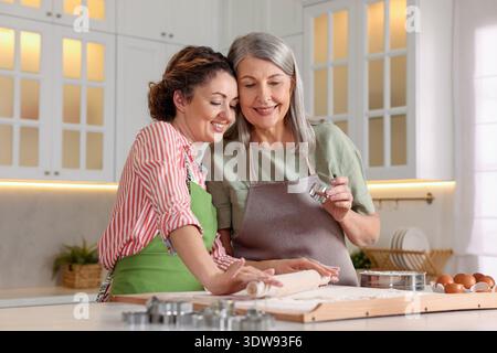Lächelnde Mutter und Tochter kochen zusammen am Tisch in der Küche Stockfoto