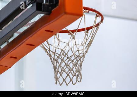 Aus nächster Nähe hinter dem Rückteil eines Basketballkörpers und Netzes mit einer weißen Wand im Hintergrund. Stockfoto