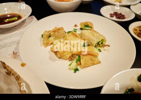 Verschiedene köstliche chinesische Gerichte im Restaurant, darunter gebratene Teigtaschen, knusprige Garnelentoast, Eierrollen und gebratene Morgenglück mit Fleisch. Stockfoto