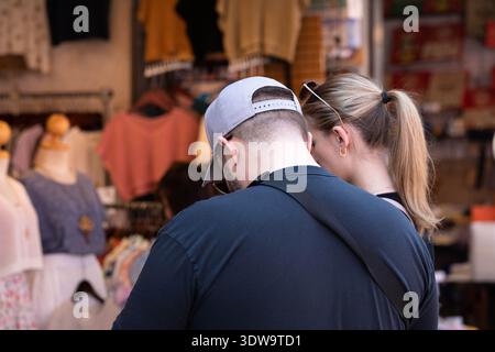 BANGKOK, THAILAND. 25. JANUAR 2026: Mann in Mütze und blauem T-Shirt auf dem lokalen Markt, soziale Interaktion im Freien, Rückansicht, auf dem Chatuchak Markt. Stockfoto