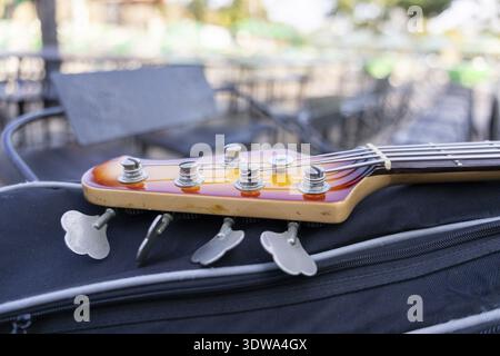 Sunburst Holzkopfstöcke der Bassgitarre liegen draußen auf dem Gehäuse. Dieses Musikinstrument mit Streichern und Stimmknöpfen hat einen klassischen Look und ist bereit für Rela Stockfoto