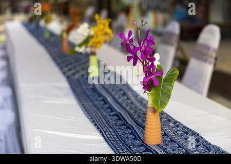 Elegante Tischdekoration mit wunderschöner Blumenorchidee in Vase für eine Veranstaltung im Freien. Festliches Arrangement auf langem Esstisch für P. Stockfoto