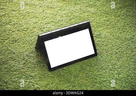 Laptop mit leerer weißer Bildschirm auf dem grünen Rasen Stockfoto
