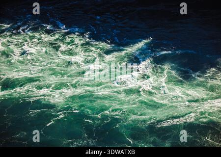 Aus nächster Nähe sehen Sie die türkisfarbenen Stromschnellen des Niagara River mit schaumigen Wellen und Sonnenlichtreflexionen Stockfoto