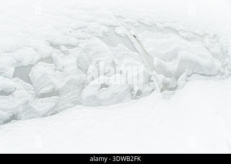 Nahtextur eines Polycarbonatgewächshauses, das nach einem Winterblizzard stark mit gefrorenem weißem Schnee bedeckt ist. Abstraktes landwirtschaftliches Muster im Freien. Stockfoto