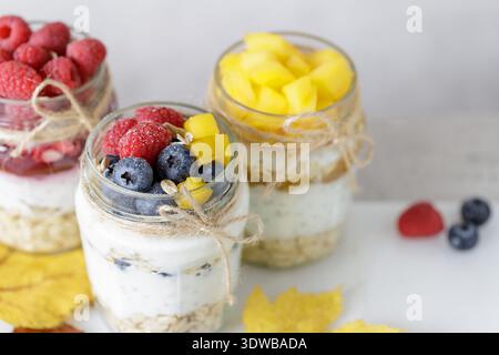 Drei Gläser Chia-Joghurtpudding mit Hafer, Beeren und Marmelade auf einem Marmorbrett. Das Konzept der gesunden Ernährung, Ernährung. Stockfoto