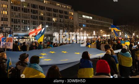 Berlin - 24. Februar 2026: Demonstranten marschieren nachts durch eine hell beleuchtete Stadtkreuzung während einer Kundgebung zur Unterstützung der Ukraine und der U Stockfoto