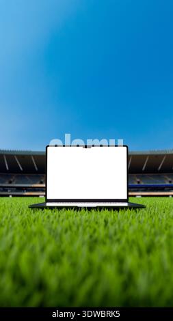Laptop mit leerem Bildschirm über dem Grasfeld in einem Fußball- und Fußballstadion. Leeres Anzeigegerät für Modell in 8k – hochauflösendes 3D-Rendering. Vertikal Stockfoto