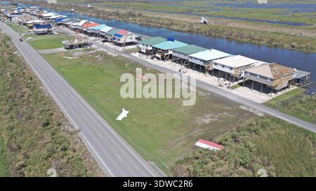 Blick aus der Vogelperspektive auf farbenfrohe Pfahlhäuser entlang der Wasserstraße, neben der Asphaltstraße, Delacroix, Louisiana, USA. Stockfoto