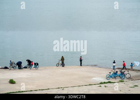 Wuhan, Provinz Hubei, China - 5. April 2023: Ein ruhiger Moment am Yangtze-Ufer in Wuchang mit einem flachen, grauen Himmel und Menschen, die die Flüsse genießen Stockfoto