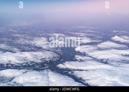 Aus der Vogelperspektive mit Blick auf eine schneebedeckte Berglandschaft mit tiefem Flusstal und Horizont Stockfoto