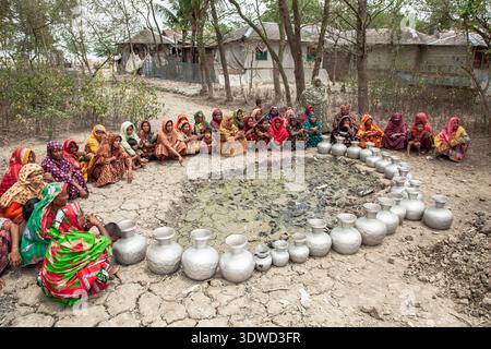 Satkhira, Bangladesch - 25. April 2025: Blick auf Frauen, die sich um einen von Krügen umgebenen, getrockneten Teich versammelten, um die gravierenden Auswirkungen der Dürre auf ihre zu verdeutlichen Stockfoto