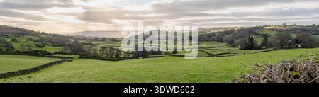 Sanfte grüne Landschaft mit Steinmauern und dramatischem bewölktem Himmelspanorama Stockfoto