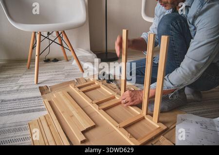Person, die flache Holzmöbel auf einem Teppich baut, um diy-Montage durchzuführen Stockfoto