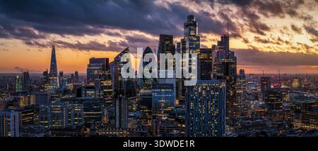 Aus der Nähe der Skyline des City of London Clusters während des Sonnenuntergangs mit Sonnenlicht, das von den modernen Fassaden des Bürobu reflektiert wird Stockfoto