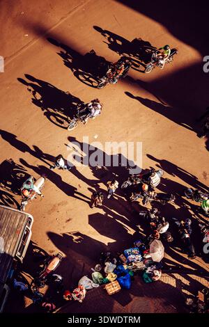 Kampala, Uganda - 28. März 2024: Blick auf Menschen, die in der Nähe von Müll auf der Straße spazieren und lange Schatten im hellen Sonnenlicht werfen. Stockfoto