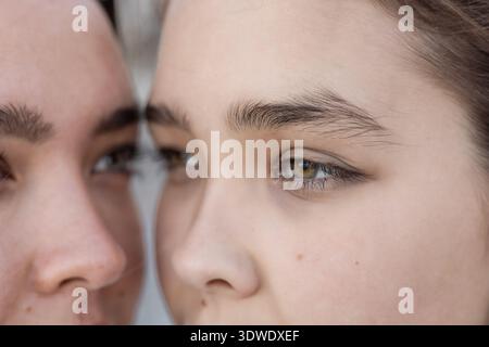 Nahaufnahme zweier Schwestern mit ausdrucksstarken Augen und aufmerksamem Ausdruck. Die Teilansicht hebt ihre Bindung und Verbindung hervor und erfasst einen Moment von en Stockfoto