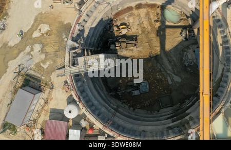Luftaufnahme einer Baustelle mit kreisförmigem Aushub für einen Tunnel, mit Sichtbarkeit schwerer Maschinen und Ausrüstung. Der Ort ist umgeben von Stockfoto